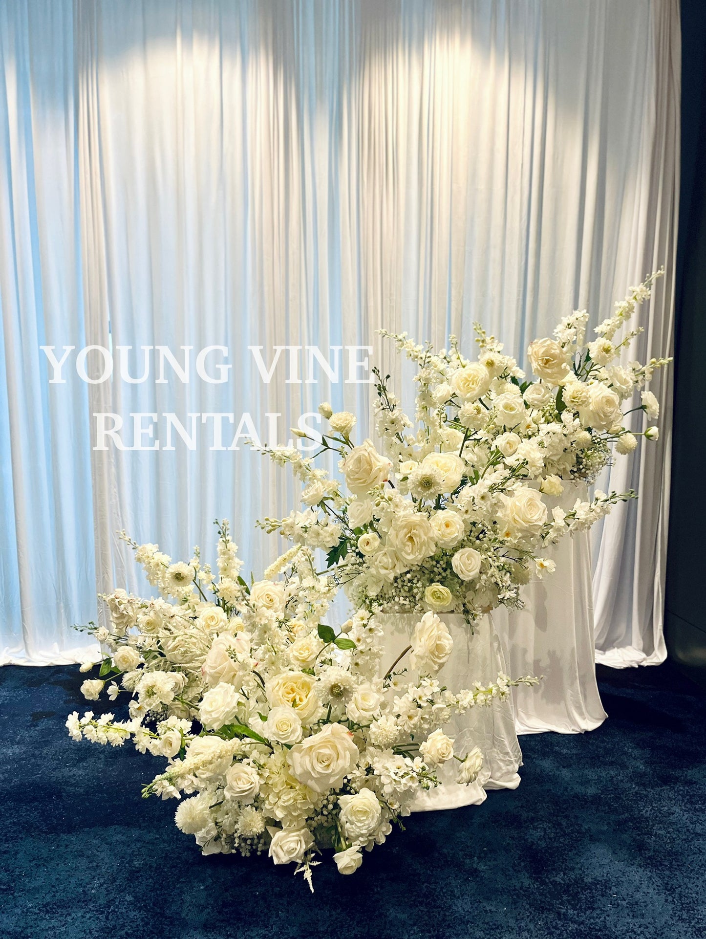Decorative Floral Arrangements in all white against a white draped backdrop