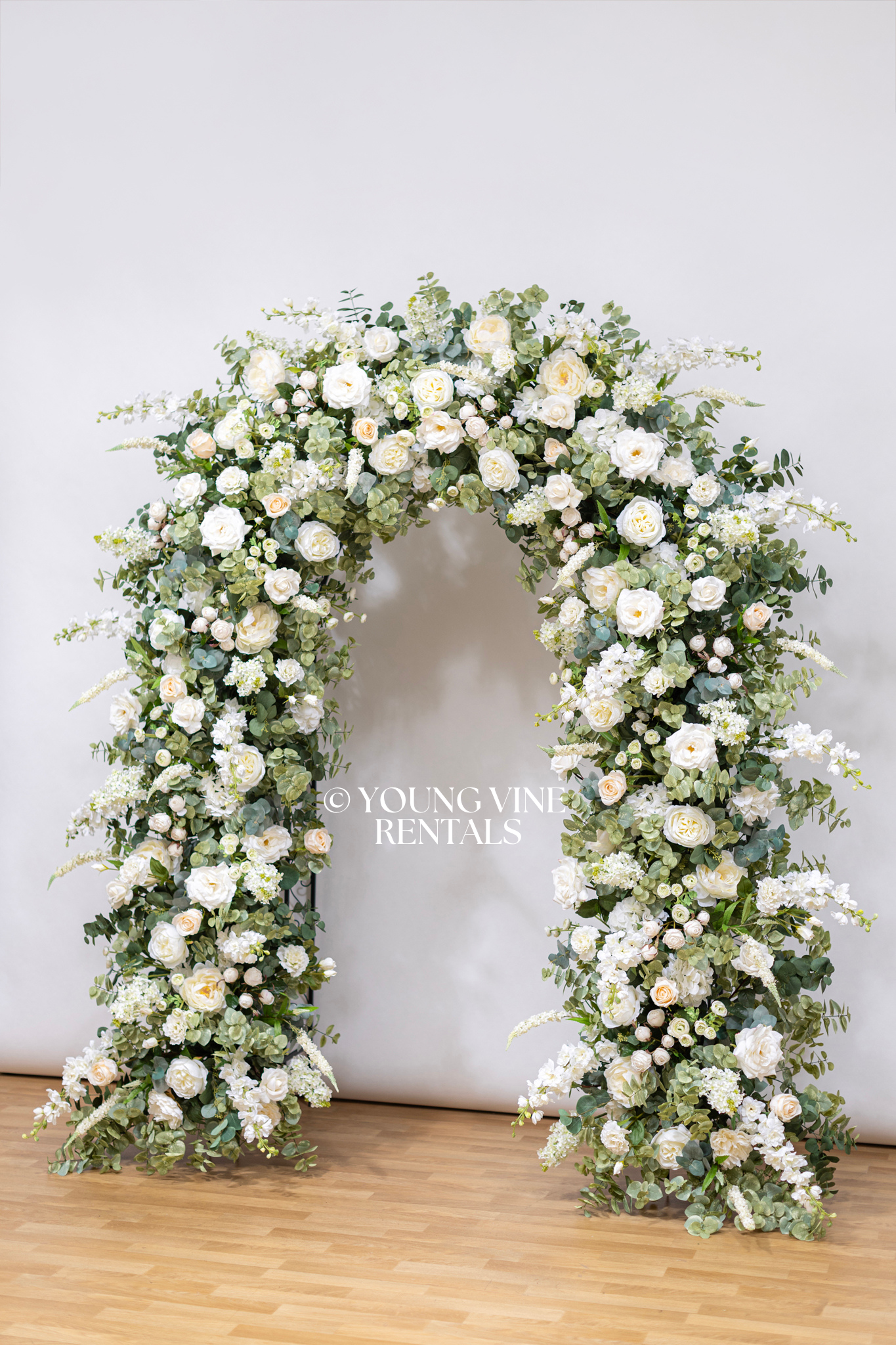 Lush, romantic, U-shaped wedding arbor studded with an abundance of ivory and white flowers and various types of eucalyptus foliage.