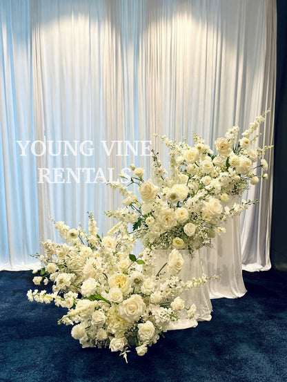 Decorative Floral Arrangements in all white against a white draped backdrop