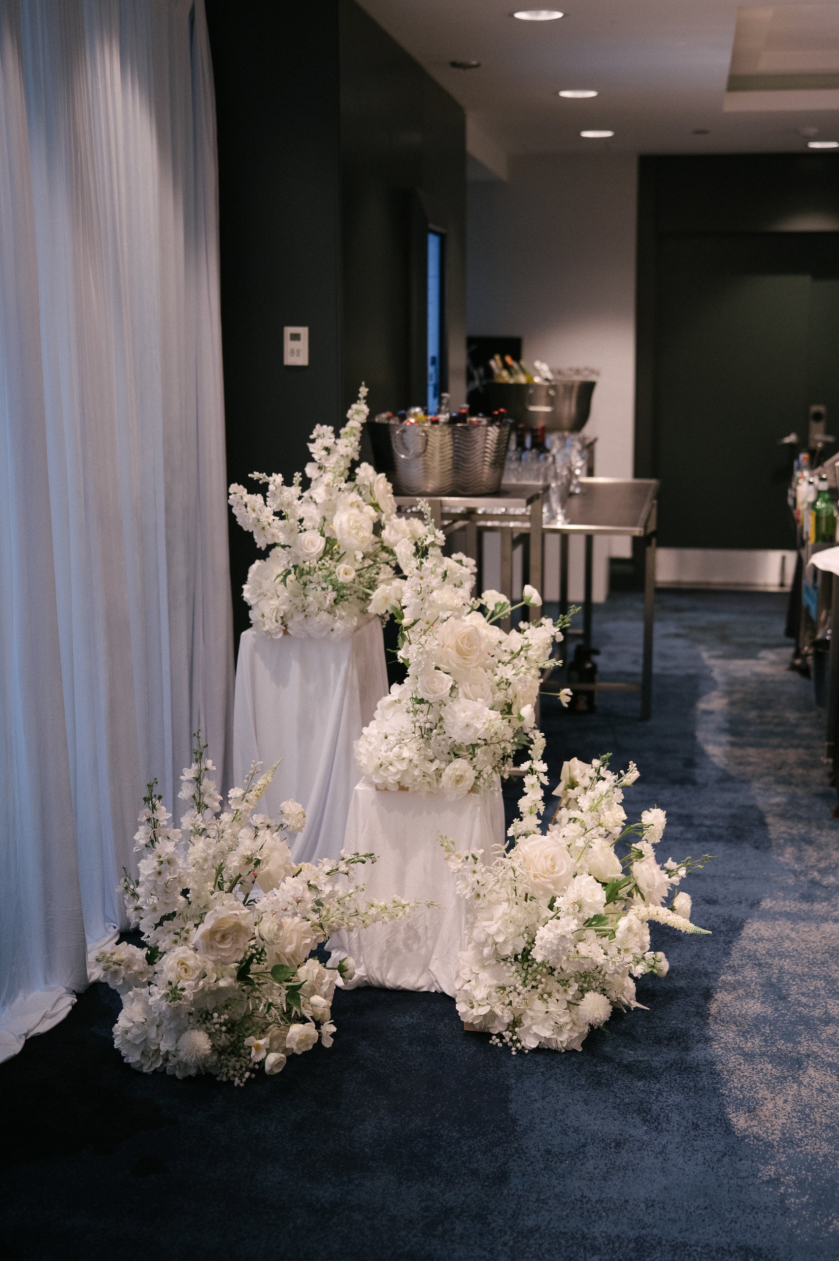 Decorative wedding floral arrangements in white with draped pedestals